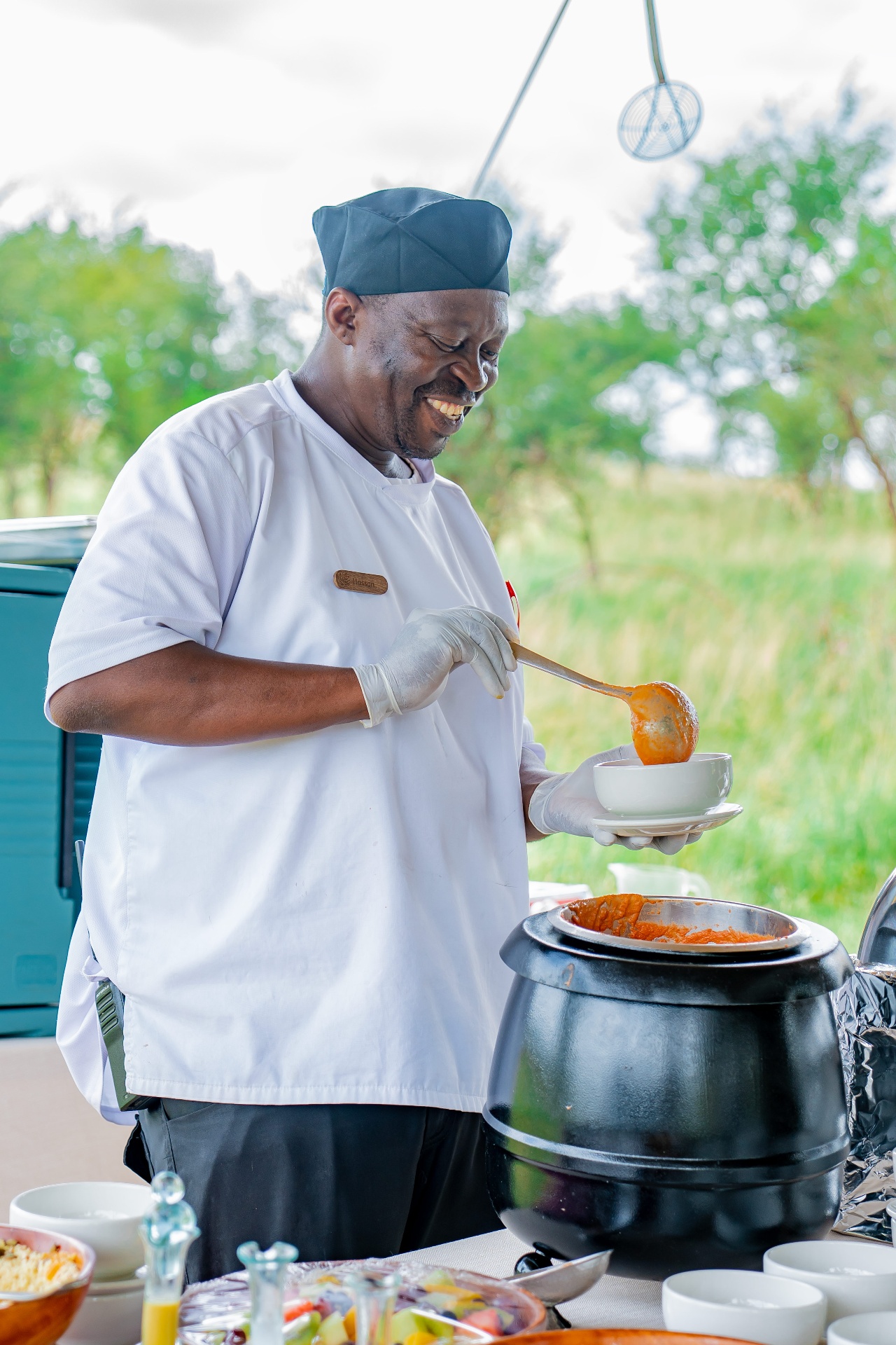 Chef Hassan ladling a Tanzanian dish at a bush kitchen