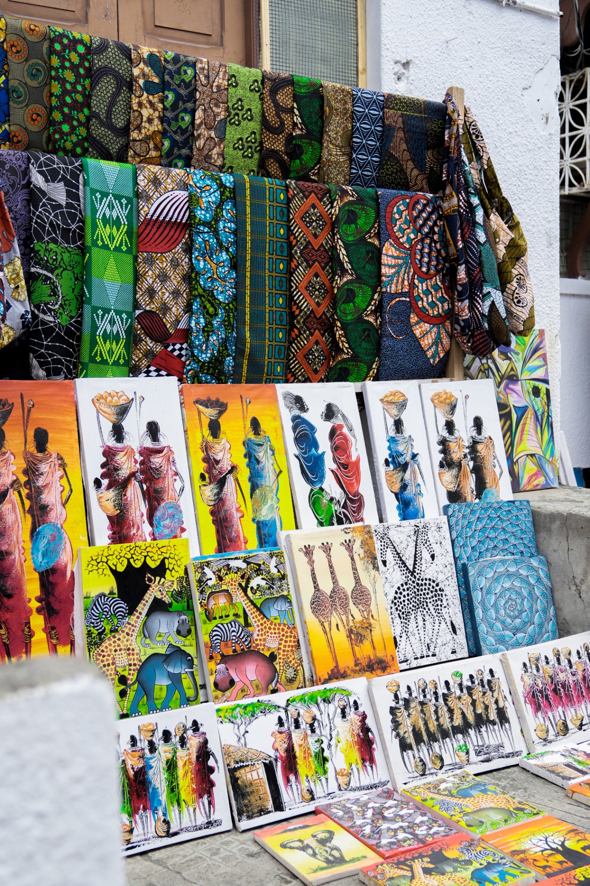 Kanga fabrics and hand-painted canvases priced in shillings at a Stone Town street stall