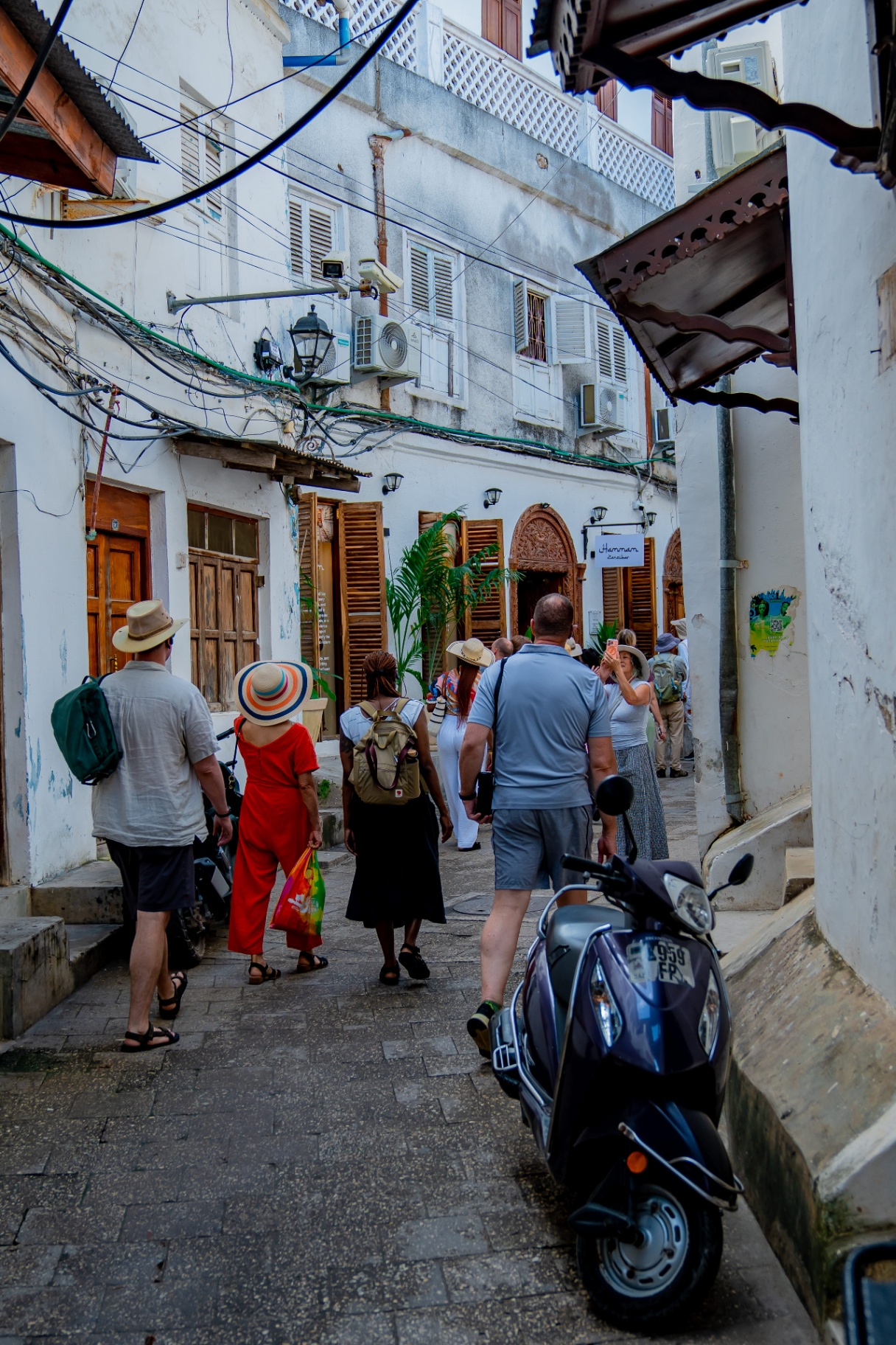 Tourists walking through a narrow Stone Town alley